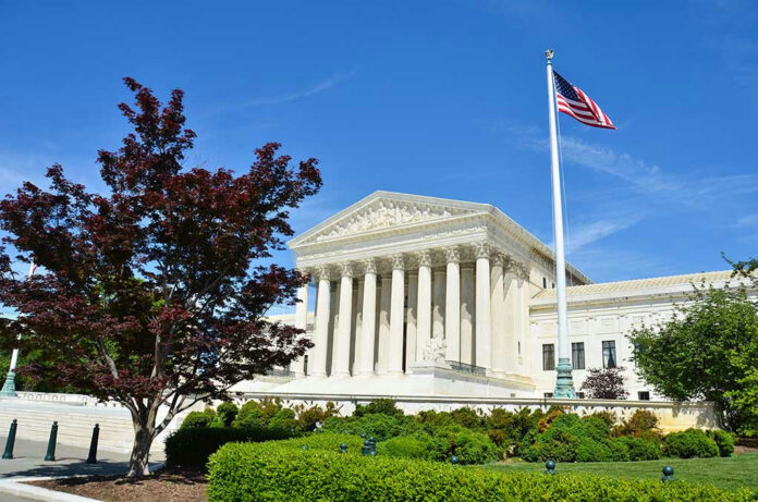 Supreme Court building with American flag and trees.