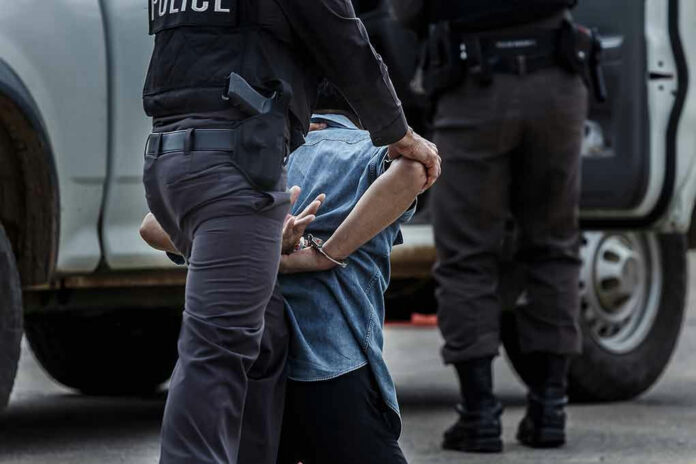 Police officer arresting and handcuffing a person.