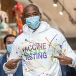 Ex-Mayor’s Legal Bills CANCELED—Political Warfare Explodes… Man wearing Vaccine and Testing hoodie, pointing at text.
