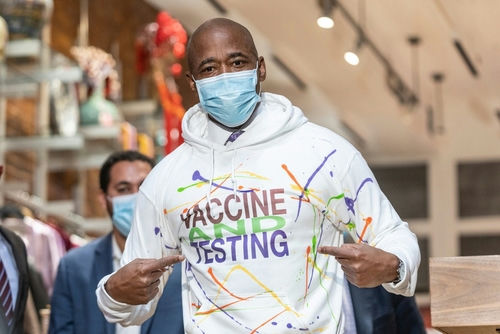 shutterstock2100895366-1jpg Man wearing Vaccine and Testing hoodie, pointing at text.