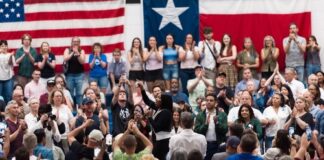 A large crowd at a political rally with people cheering and taking photos