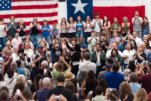 A large crowd at a political rally with people cheering and taking photos