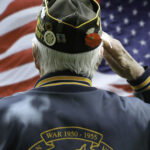 Veteran saluting in front of American flag.