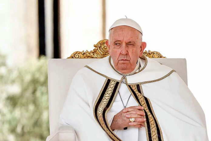Elderly man in white robe sitting on chair.