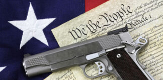 Handgun resting on historical document with American flag backdrop