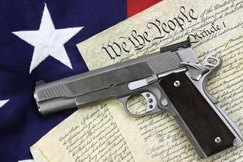 Handgun resting on historical document with American flag backdrop