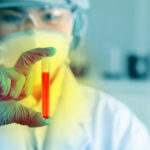Scientist holding a test tube with red liquid in a laboratory setting