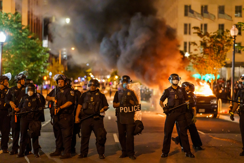 Many,Protesters,Gathered,Around,The,White,House,To,Demand,Justice Police officers in riot gear facing a chaotic protest scene with smoke and fire
