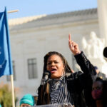 Speaker raises hand while addressing crowd at outdoor rally