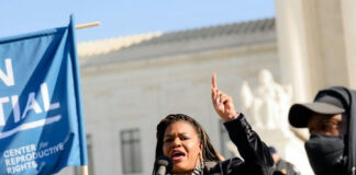 Speaker raises hand while addressing crowd at outdoor rally