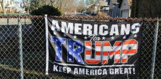 Americans for Trump banner on a fence with flags