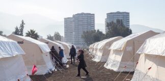 A temporary shelter area with tents and people walking around