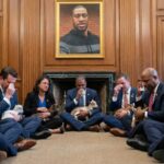 Politicians sitting on the floor holding goats in a solemn gathering