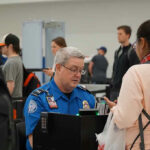 TSA agent checking a passengers documents at airport.