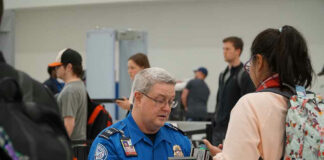 TSA agent checking a passengers documents at airport.