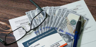 Medicare card with cash, documents, glasses, and pen.