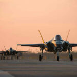 Jets on runway at sunset.