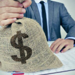 Person holding burlap bag with dollar sign.
