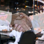 Ceasefire Deal With Iran Triggers Political Firestorm in Washington Two people shaking hands; men in background discussing.