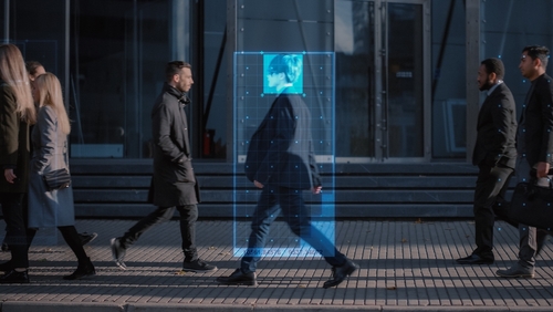 A digital overlay of a persons face on a pedestrian walking in an urban environment