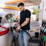 Man fueling a silver car at a gas station
