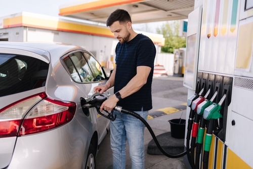 Man fueling a silver car at a gas station