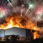 Quake-Force BLAST Rattles Small Island A large building engulfed in flames with fireworks in the sky
