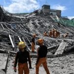 Rescue workers survey collapsed building debris
