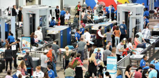 Crowd at an airport security checkpoint with TSA officers.