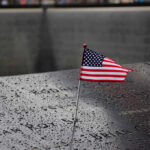 American flag on a rainy memorial nameplate.