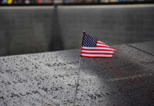 American flag on a rainy memorial nameplate.