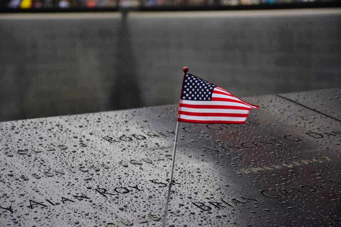 574569265 American flag on a rainy memorial nameplate.