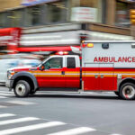 Woman BIRTHS Baby in the Middle of the Road! Red ambulance driving quickly through a city street.