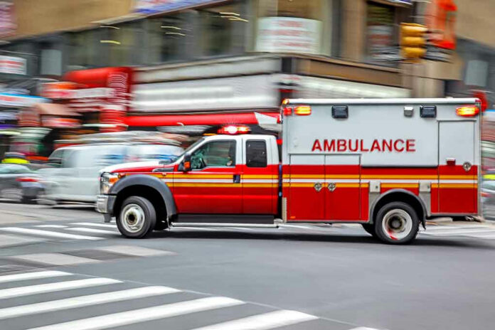 690581653 Red ambulance driving quickly through a city street.