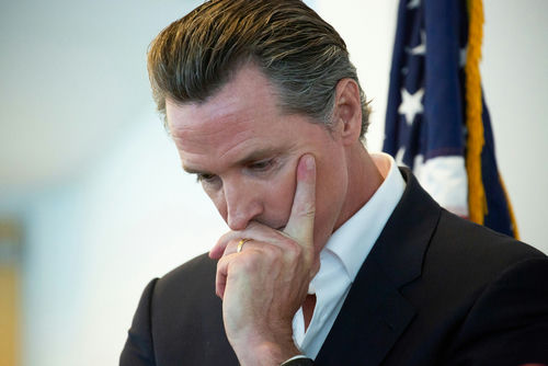 shutterstock1747778459-2jpg Man in suit thinking with hand on face near a U.S. flag