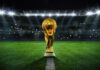 Golden trophy on soccer field under stadium lights
