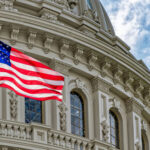 US flag waving in front of Capitol building.