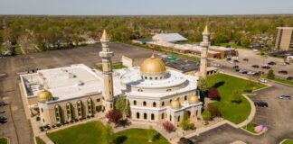 Aerial view of a mosque with golden domes and minarets surrounded by greenery