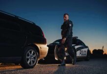 Police officer standing near patrol car during twilight traffic stop