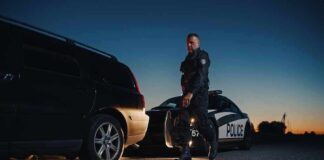 Police officer standing near patrol car during twilight traffic stop