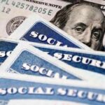 Social security cards and a hundred dollar bill arranged together