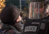 protester faces police officer in riot gear