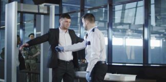 airport security officer patting down a man at a metal detector