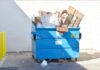 Blue dumpster overflowing with cardboard boxes