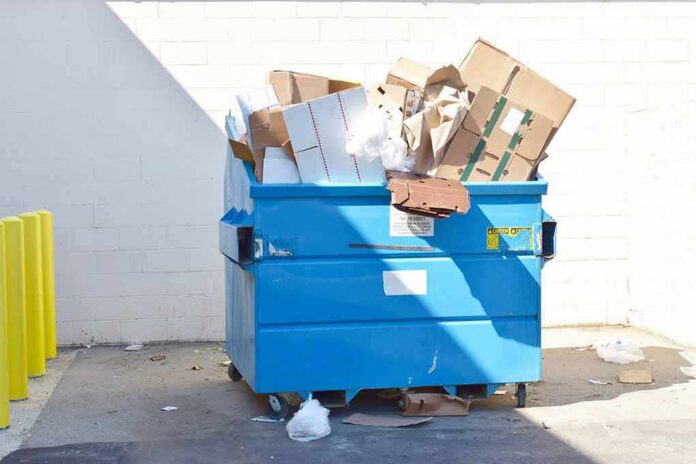 Blue dumpster overflowing with cardboard boxes