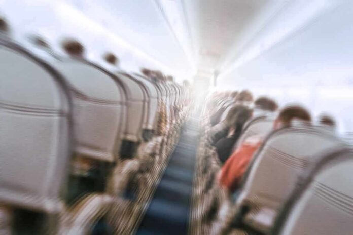 shutterstock_1073612693 Airplane cabin aisle with blurred passengers and seats