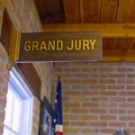 Holdout Juror ATTACKED For Being Republican Grand jury sign in a brick-walled hallway