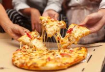 Popular Pizza Chain SHUT DOWN After Meth Trafficking Scandal Hands pulling cheesy pizza slices from a box