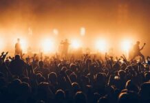 Radio Stations Pull Artist Over Controversy – Fans Erupt! Rock band performing on stage with bright backlights and cheering crowd