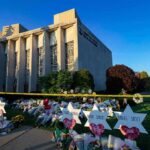 Synagogue exterior with memorial flowers and star-shaped tributes on lawn
